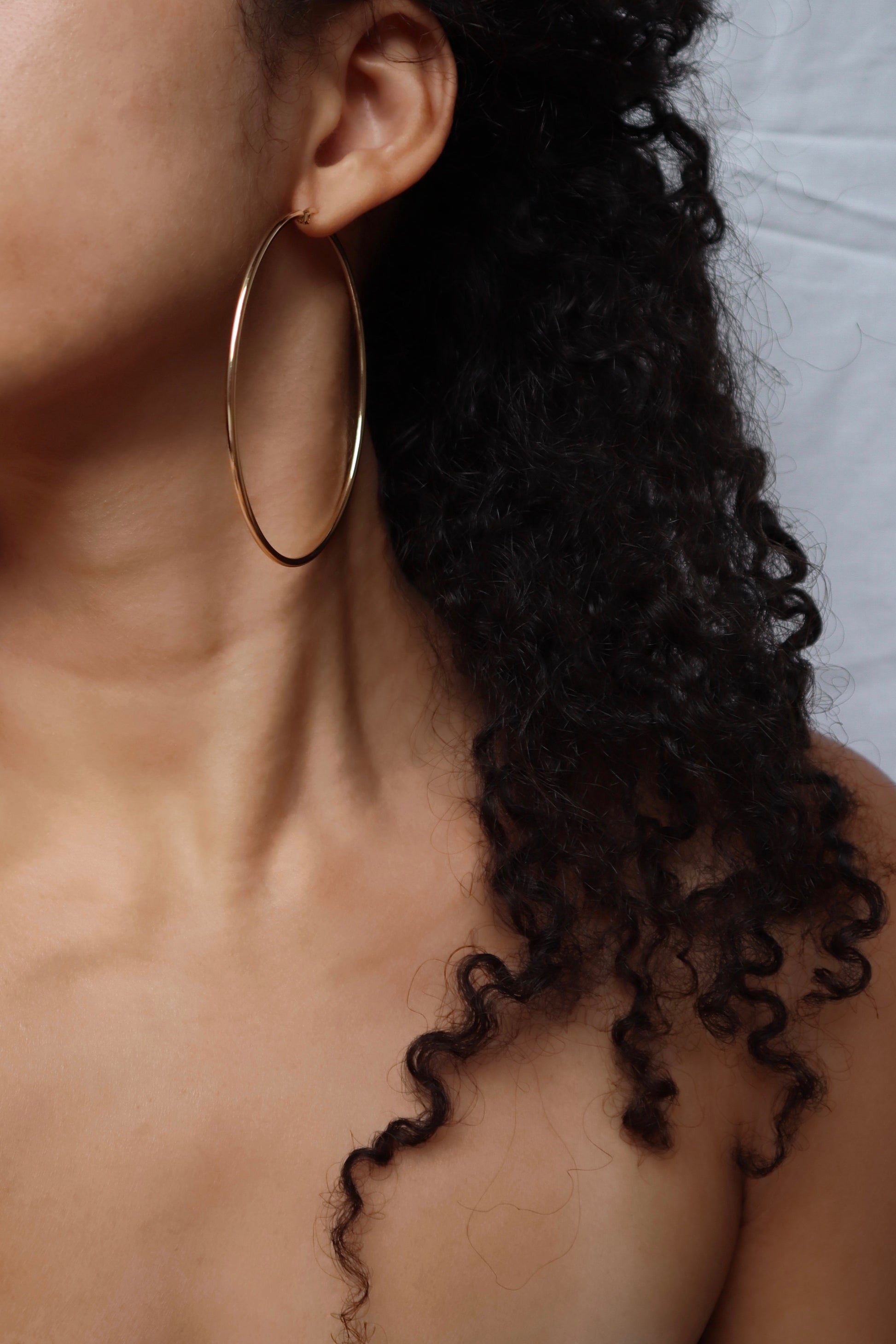 Model wearing 70mm 18K gold plated hoop earrings