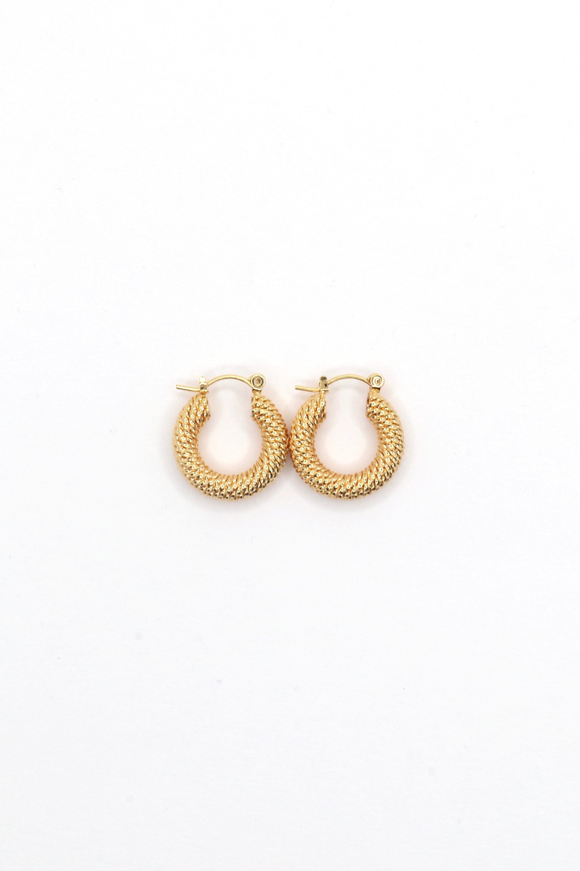 Close-up of 18K gold plated 20mm twisted hoop earrings on white background by Nayda De Jesus