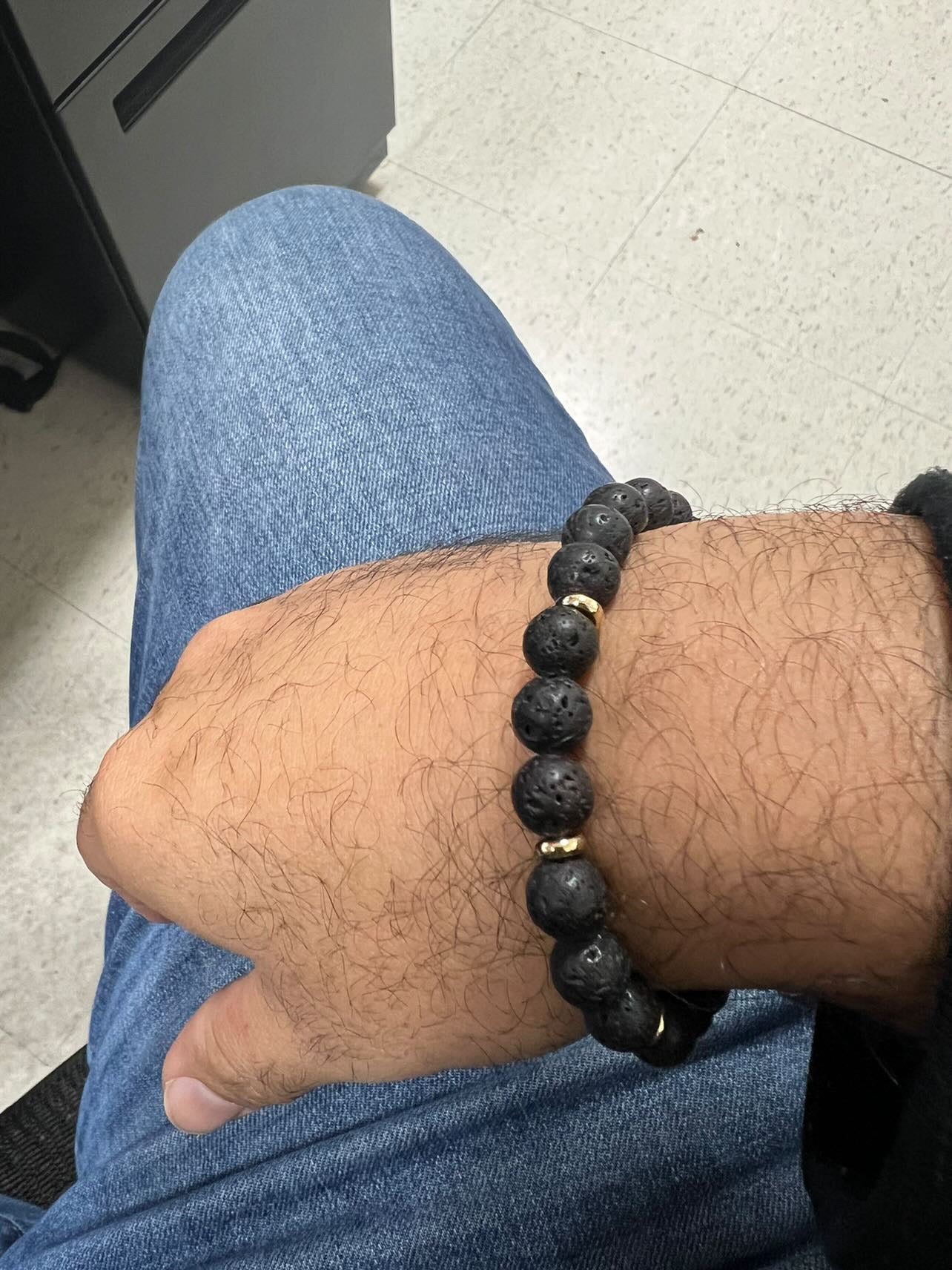 Wrist shot of black lava bead and gold bracelet by Nayda De Jesus