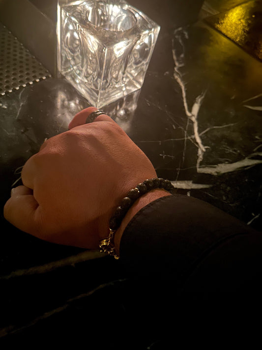 Wrist shot of black lava bead and gold bracelet by Nayda De Jesus
