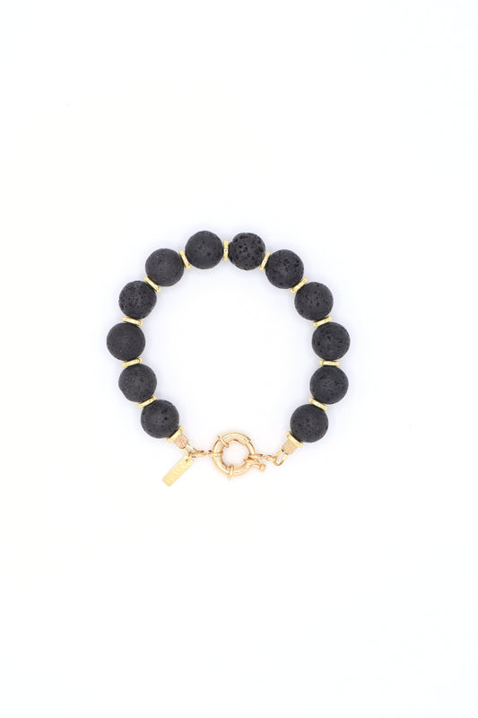 Black lava bracelet with gold accents laying flat on a white background by Nayda De Jesus