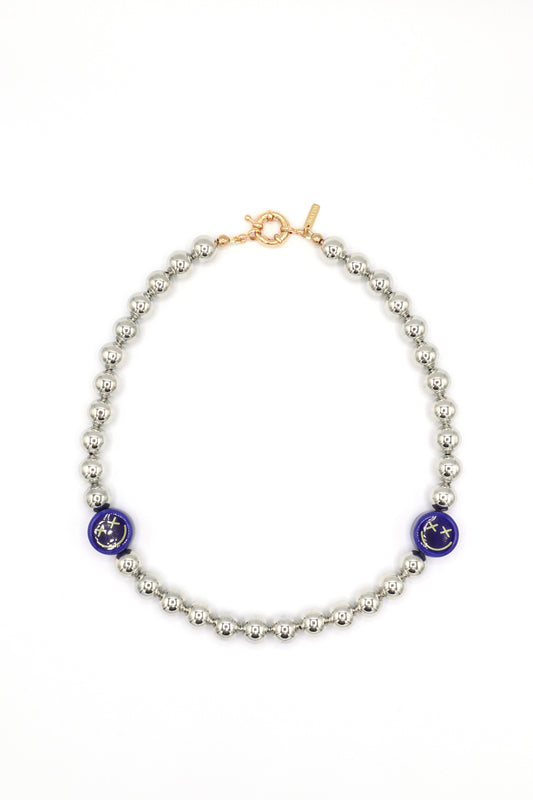 Close-up of ceramic blue smiley face charm with crossed eyes on necklace
