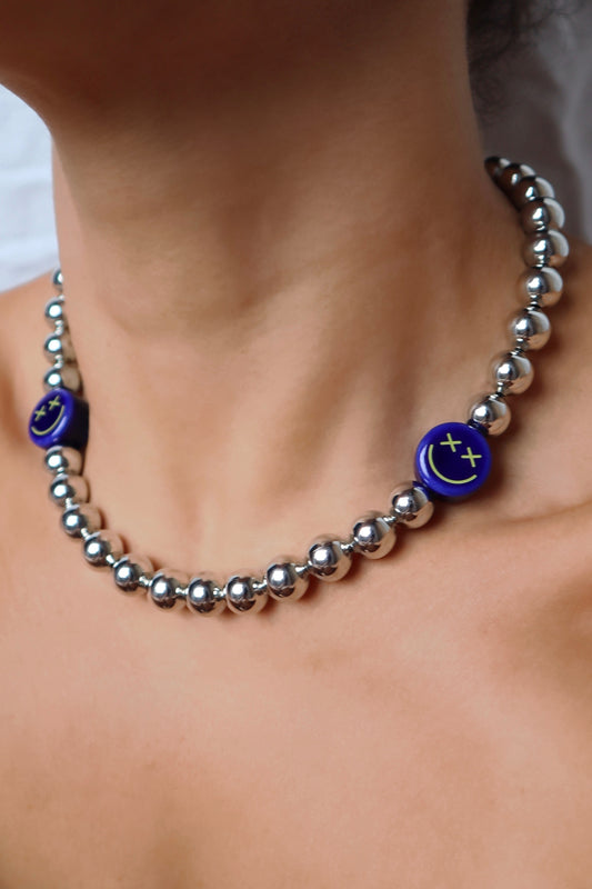 Crossed eyes blue smiley charm necklace displayed on model