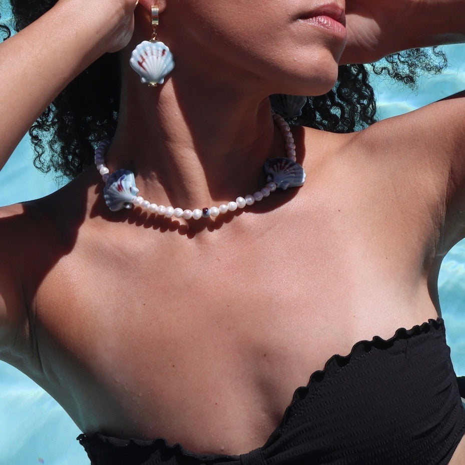 Model wearing gold huggies with blue sea shell charm, handmade jewelry