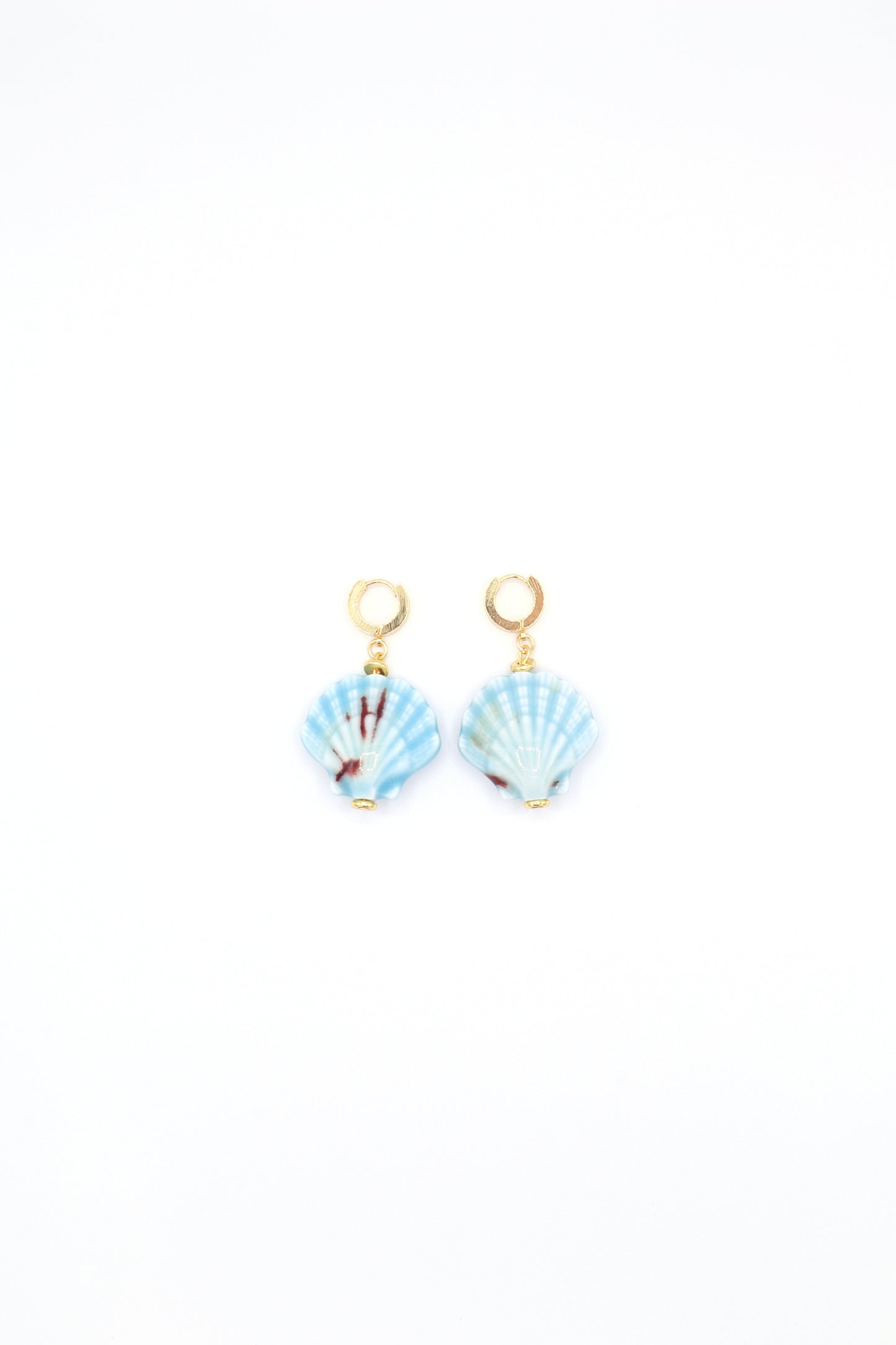 Flat lay of 18K gold plated huggie earrings with ceramic sea shells