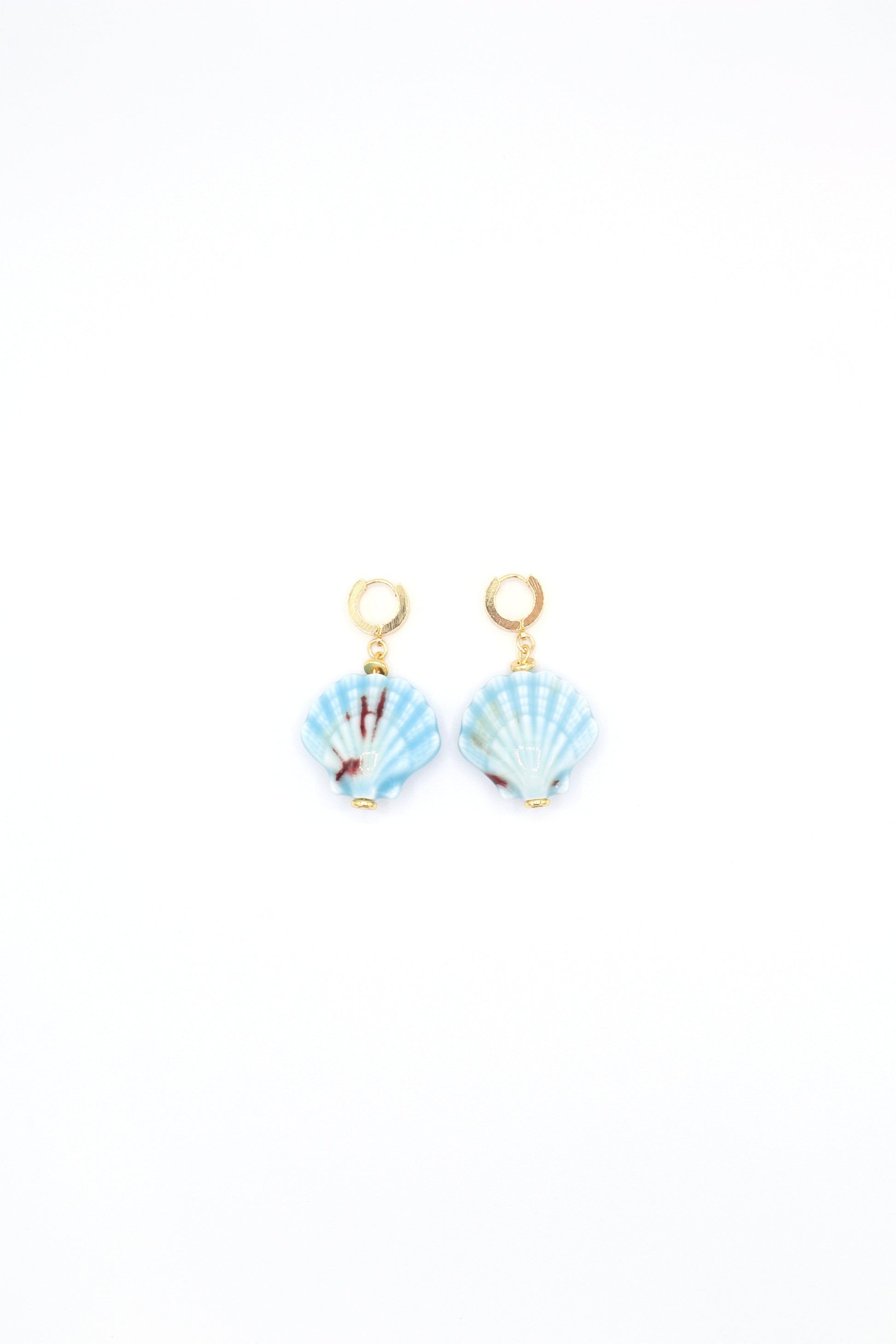 Flat lay of 18K gold plated huggie earrings with ceramic sea shells