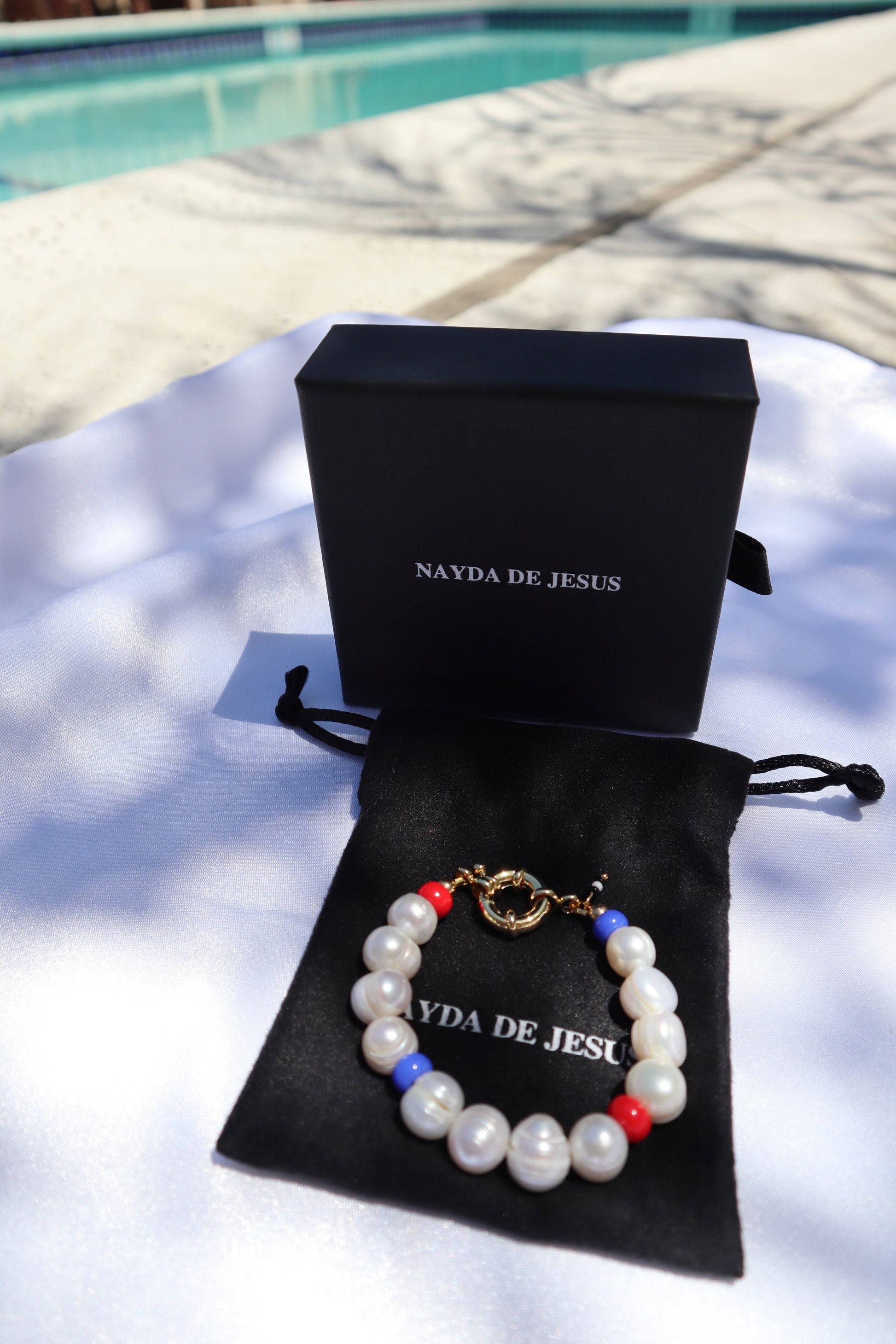 Statement bracelet with red and blue accents and white pearls on jewelry box