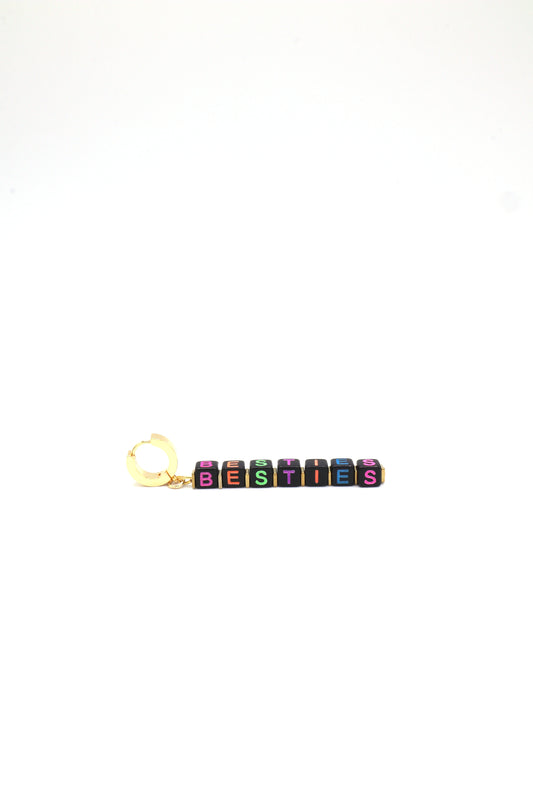 Close-up of gold huggie earrings with neon cube letters spelling Besties
