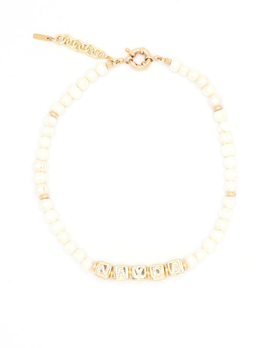 Flat lay of custom pearl necklace with 24K gold rhinestone letter charms