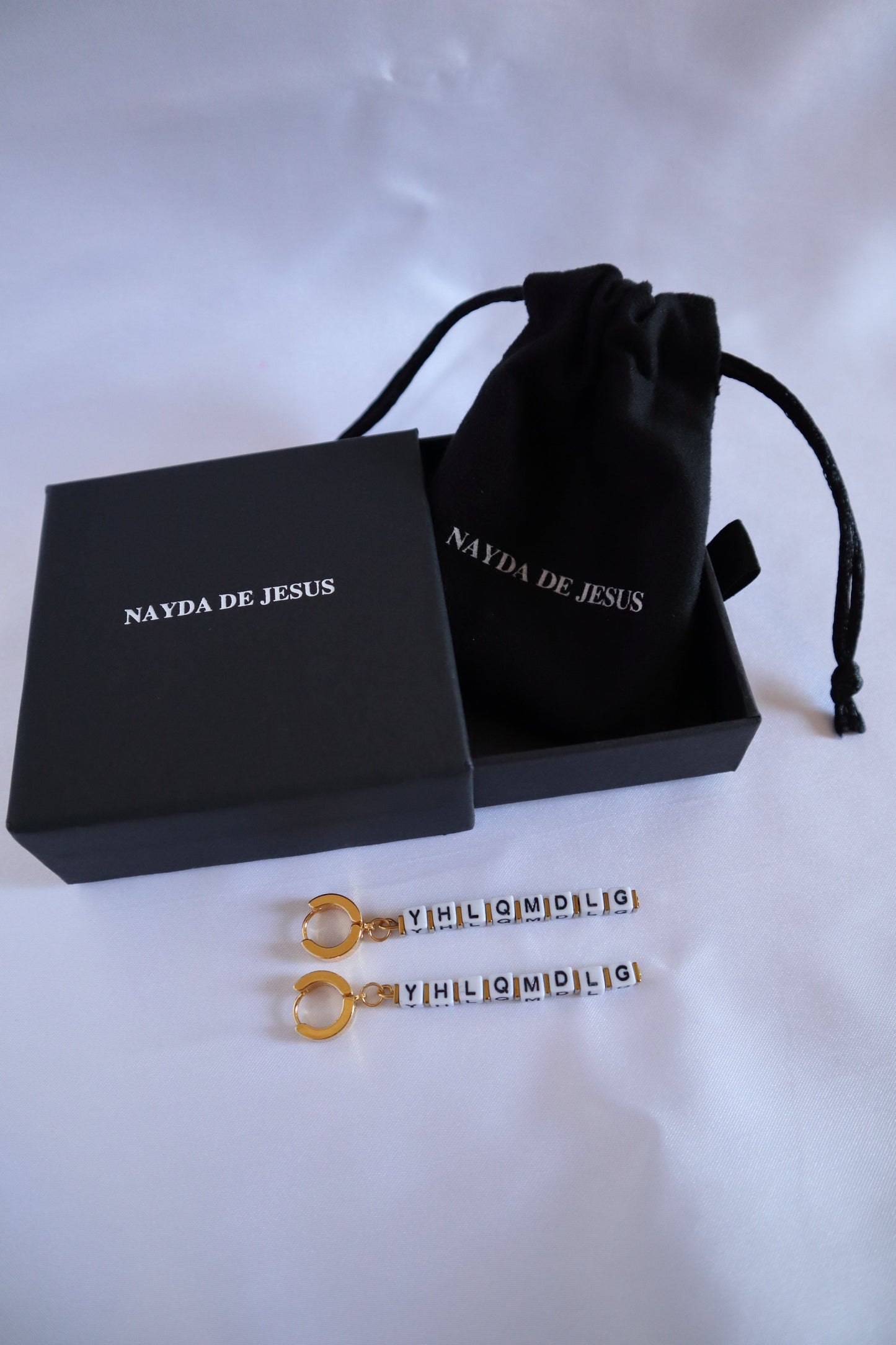 Customizable gold letter charm earrings inspired by Bad Bunny on jewelry box