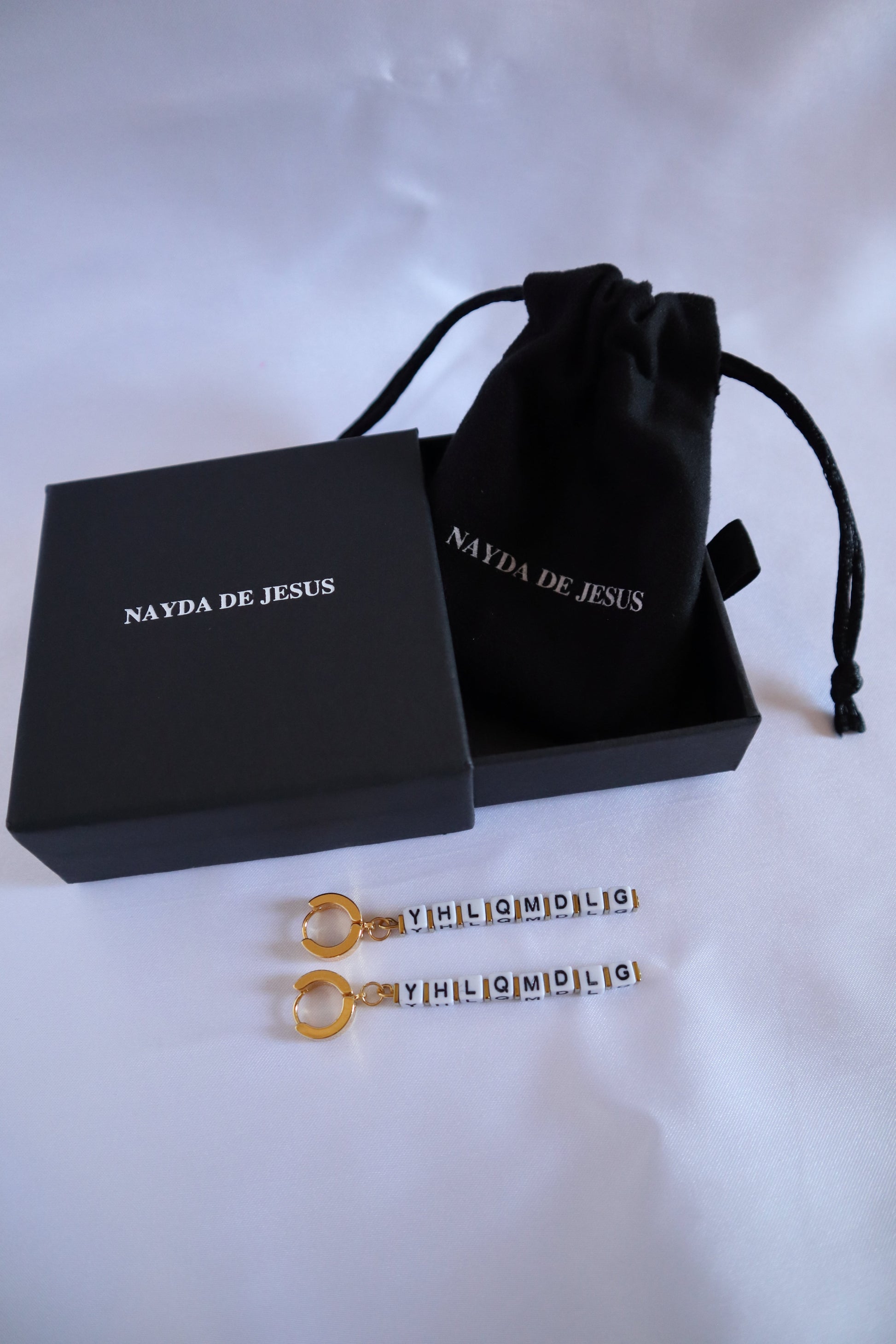 Customizable gold letter charm earrings inspired by Bad Bunny on jewelry box