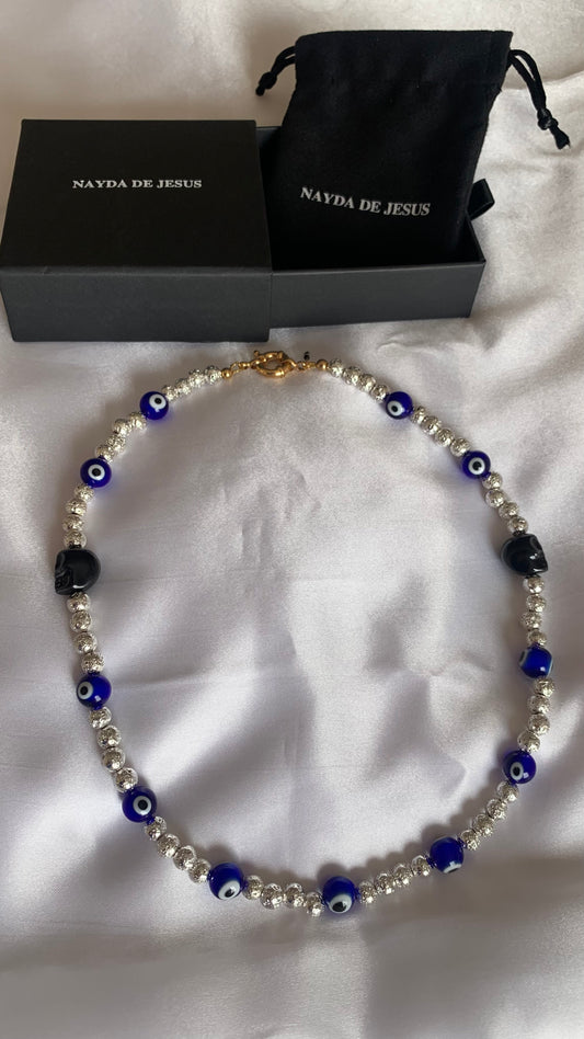 Unique necklace featuring glass evil eye, ceramic skull, and metallic beads