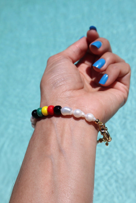 Wrist shot of rasta-inspired bracelet with glass beads and freshwater pearls by pool  by Nayda De Jesus