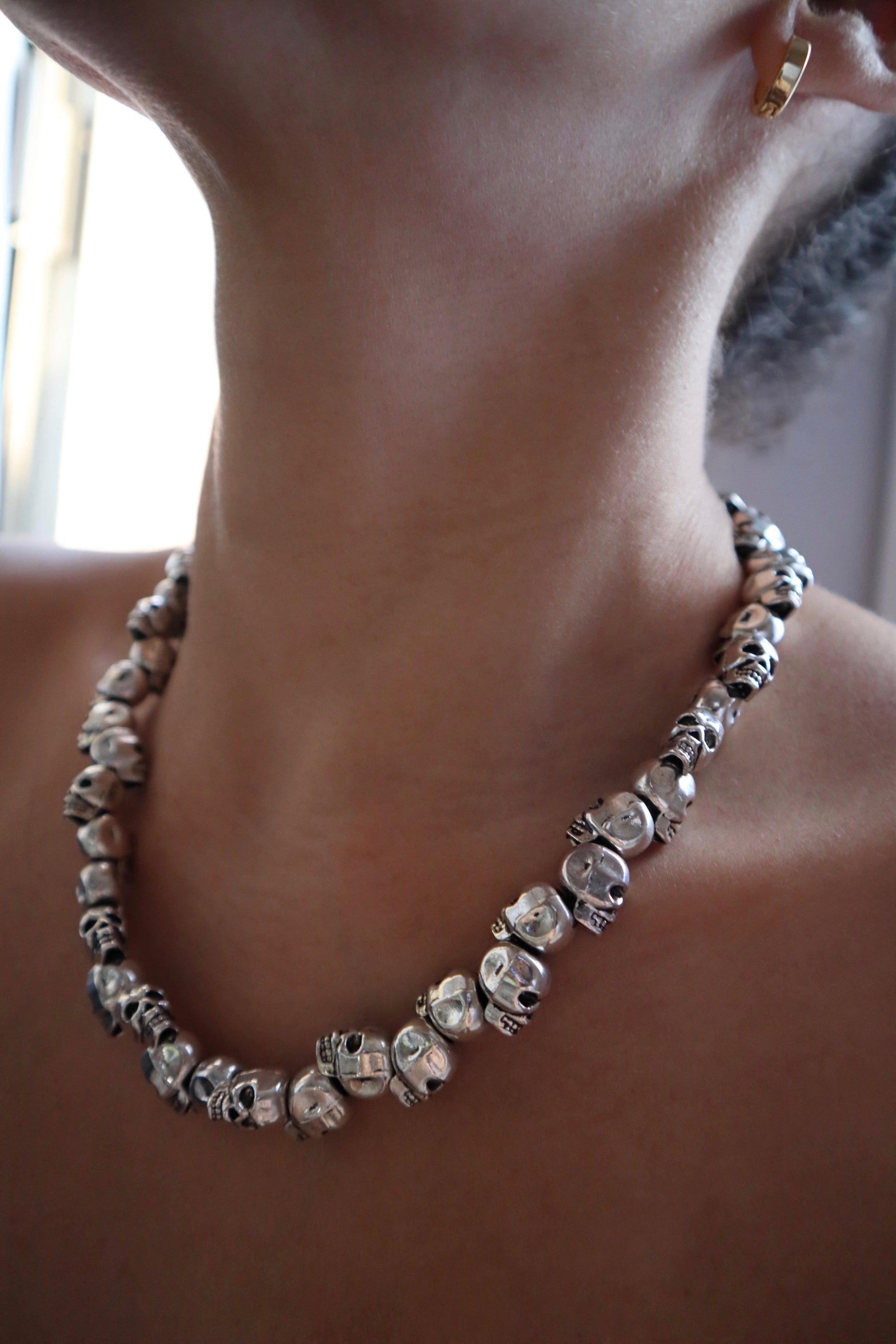 Handmade silver metal skull necklace on model