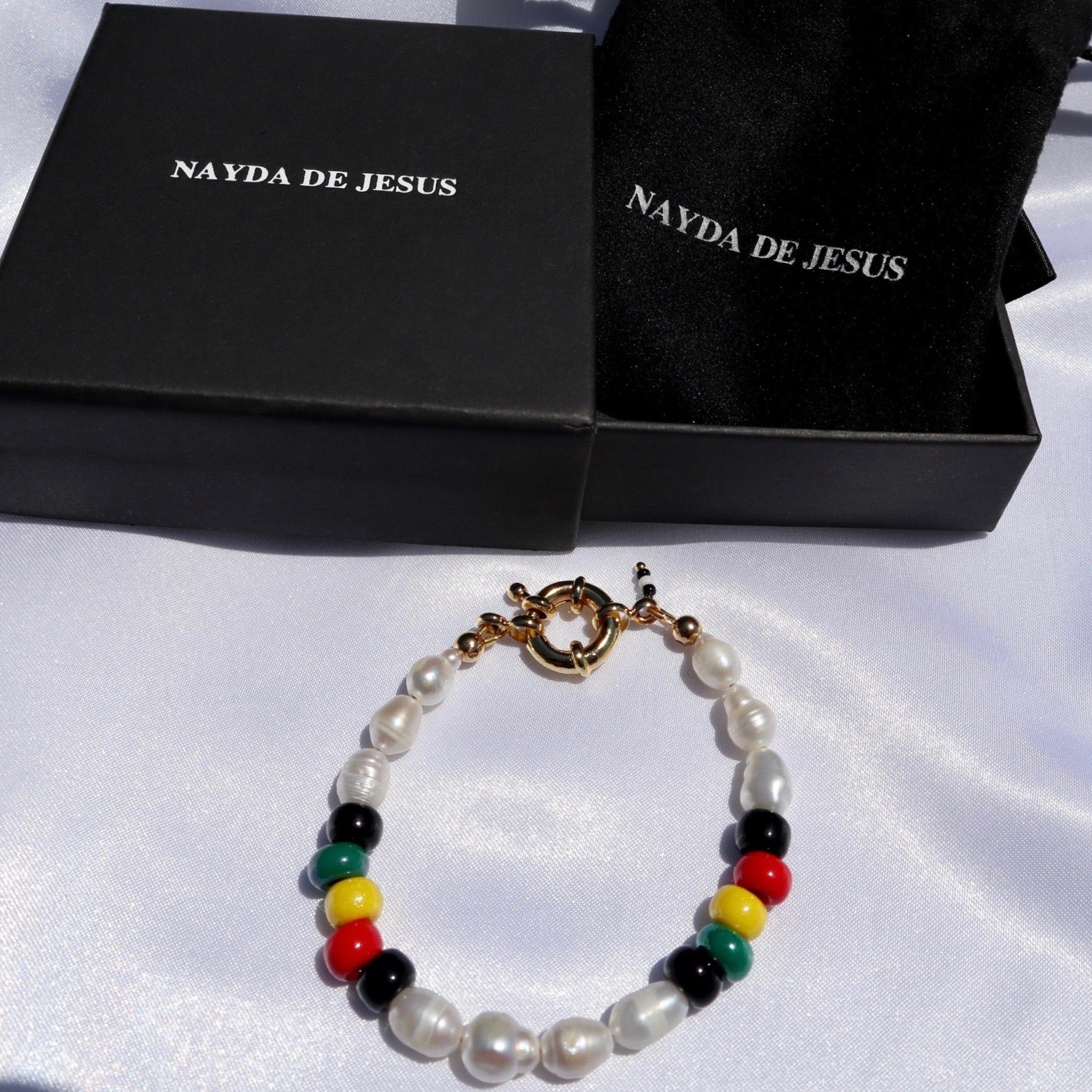 Rasta-inspired bracelet with glass beads and freshwater pearls displayed on Nayda De Jesus jewelry box