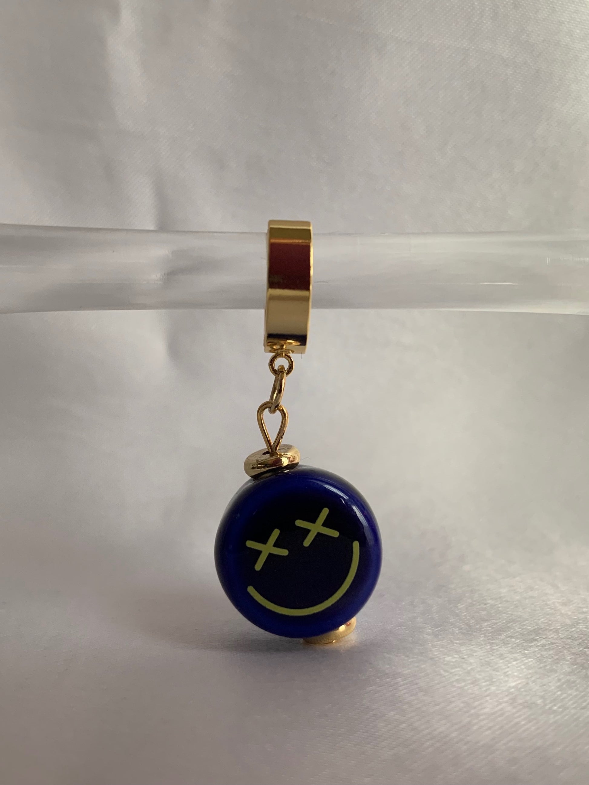 ceramic-smiley-crossed-eyes-smiley-face-18K-gold-plated-dangle-huggies-hoop-earrings-on-prop