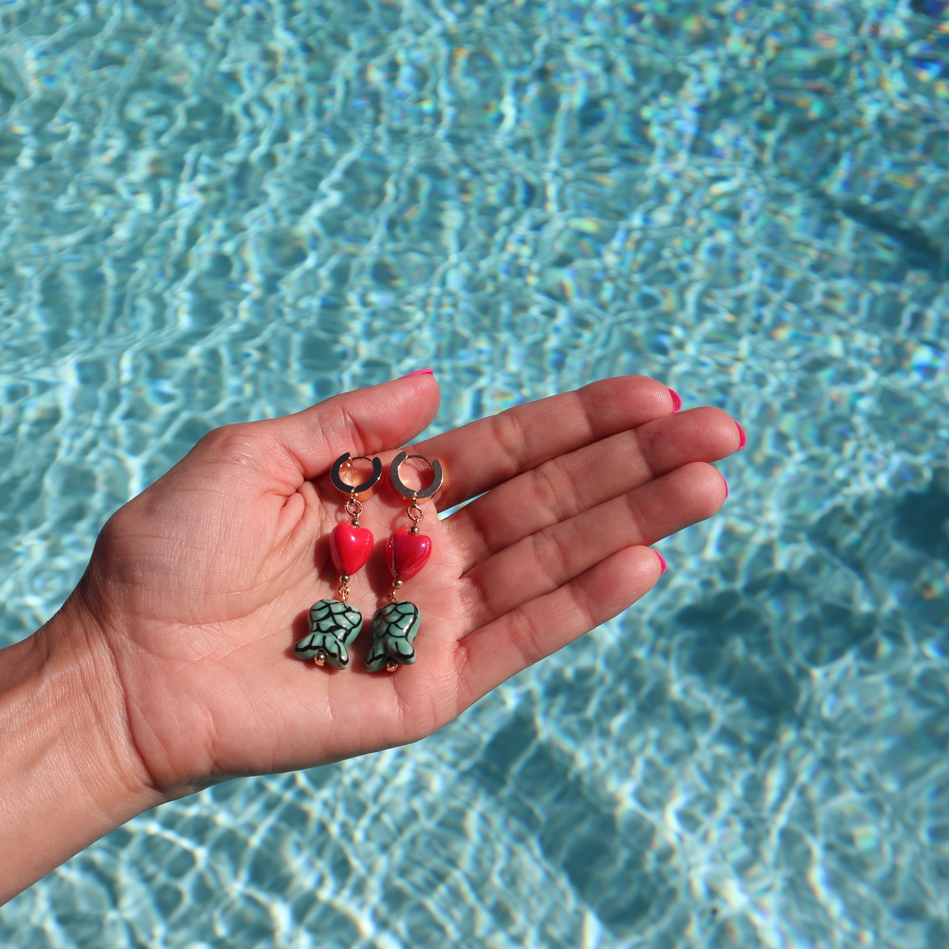 lifestyle-photo-by-pool-of-karol-g-manana-sera-bonito-teles-earrings-18-k-huggies-hoops-earrings-ceramic-heart-and-mermaid-tail-beads-by-latina-artist-nayda-de-jesus