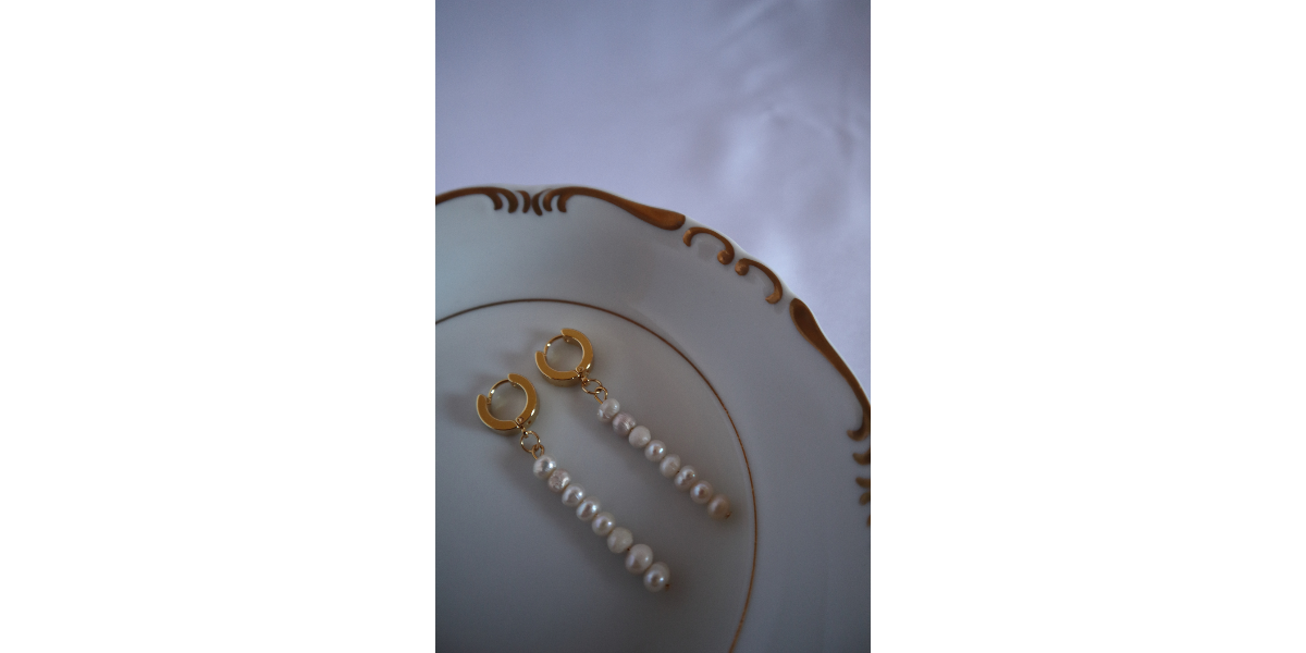 Handmade freshwater pearls earrings on a decorative plate with a white background