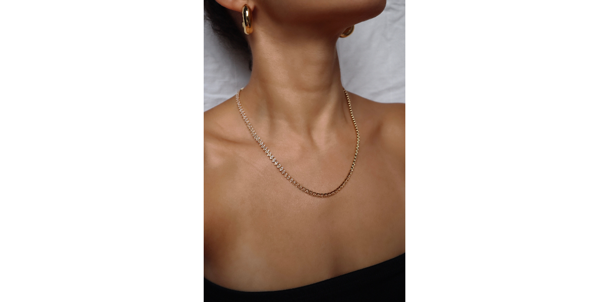 Gold necklace on a woman against a neutral background