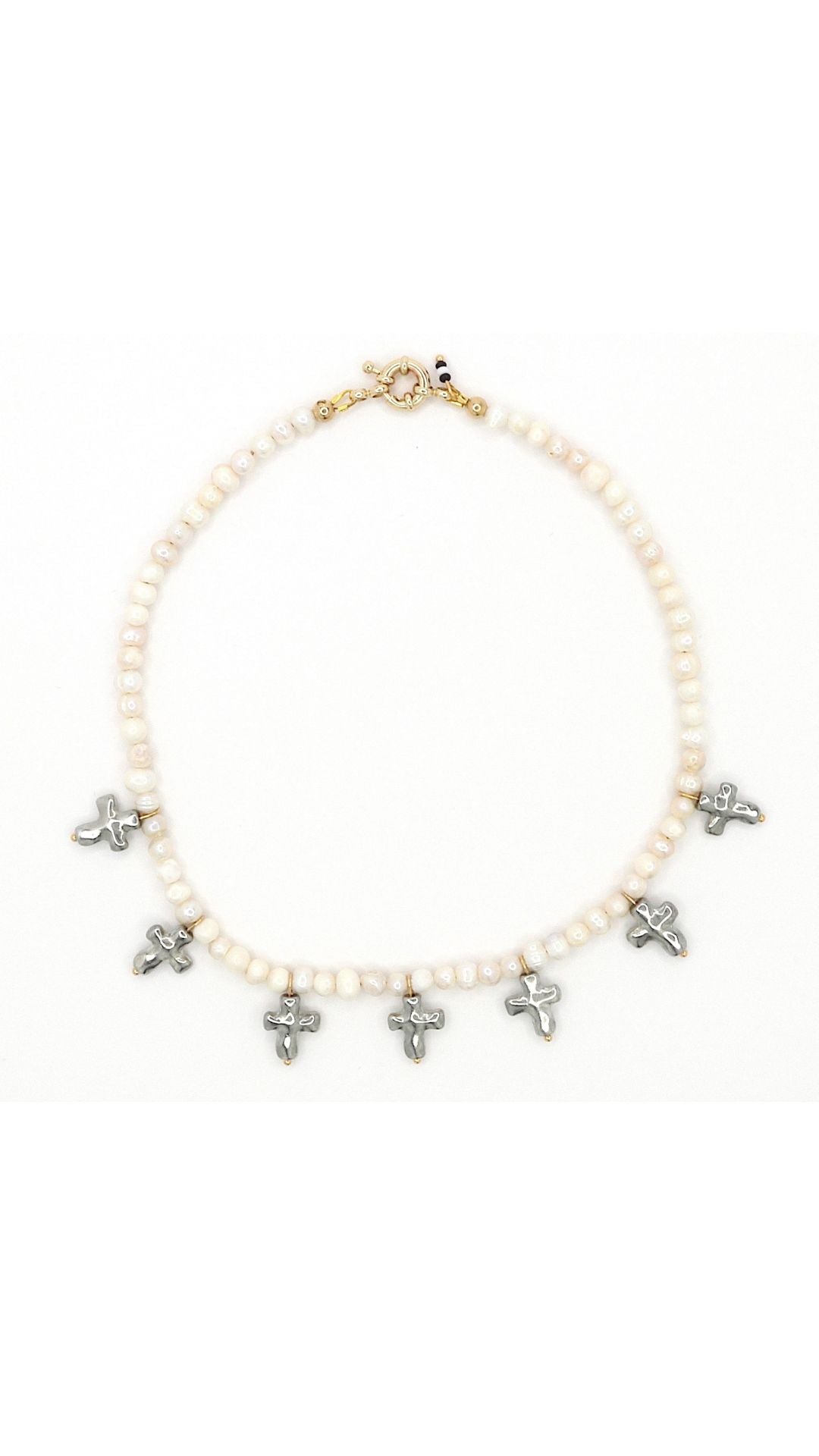 Close-up of silver cross and freshwater pearl necklace by Nayda De Jesus