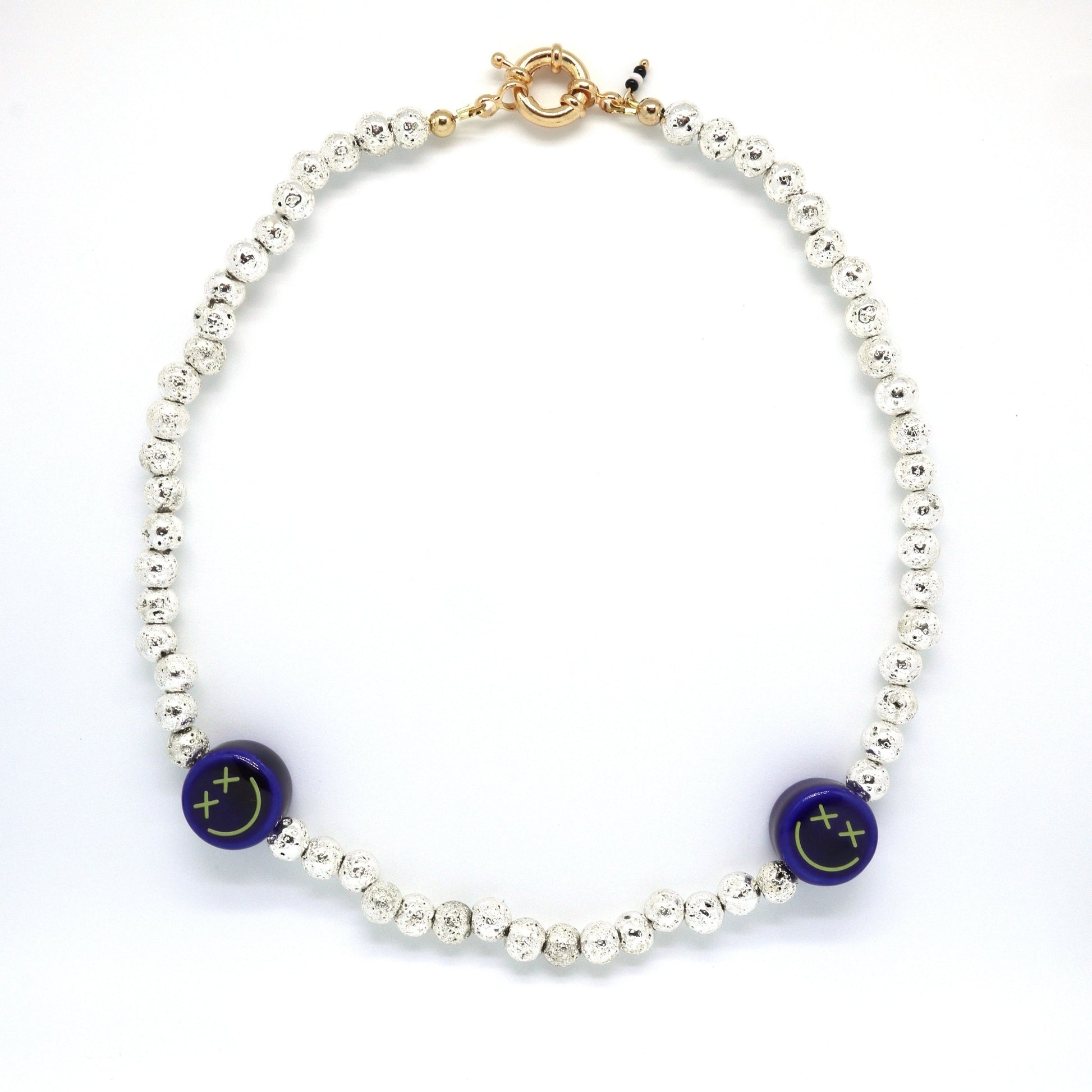 the-b612-necklace-made-with-blue-crossed-eyed-ceramic-smiley-face-and-metallic-lava-beads-along-18-k-gold-filled-spring-clasp-closure-by-latina-artist-nayda-de-jesus